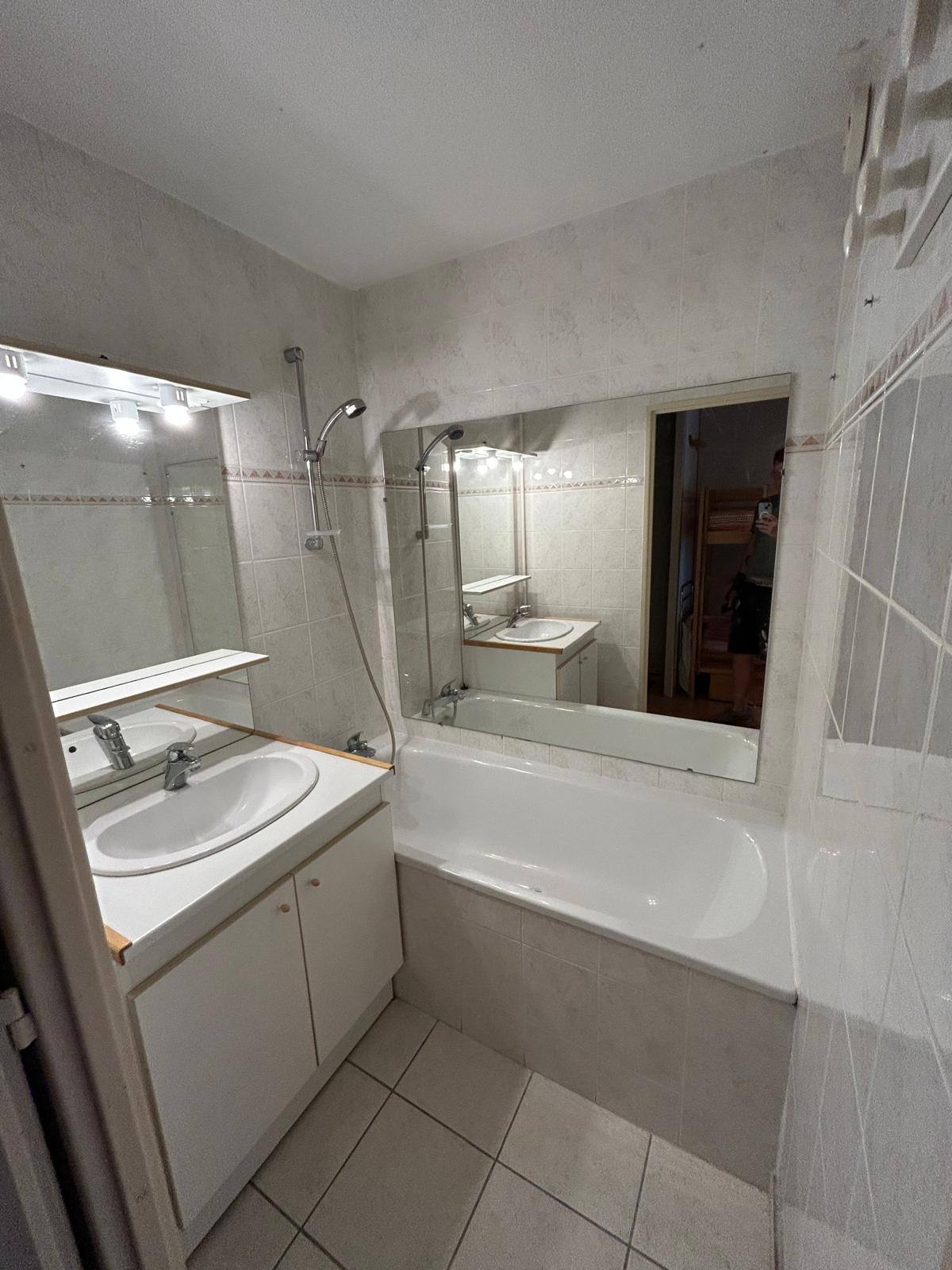 Salle de bain avant rénovation à Villar-Saint-Pancrace : ancienne baignoire, faïence blanche datée et meuble vasque vieillissant
