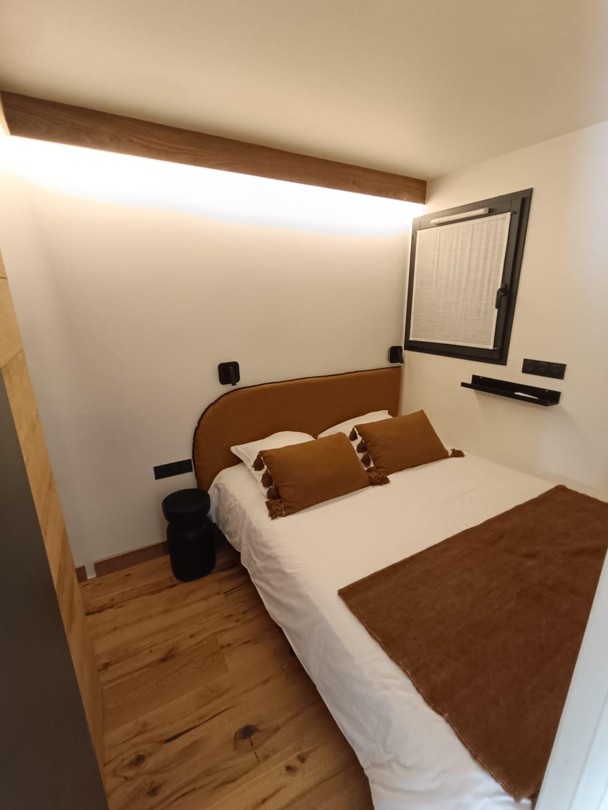 Chambre rénovée aux finitions soignées : tête de lit en bois, parquet et éclairage LED intégré