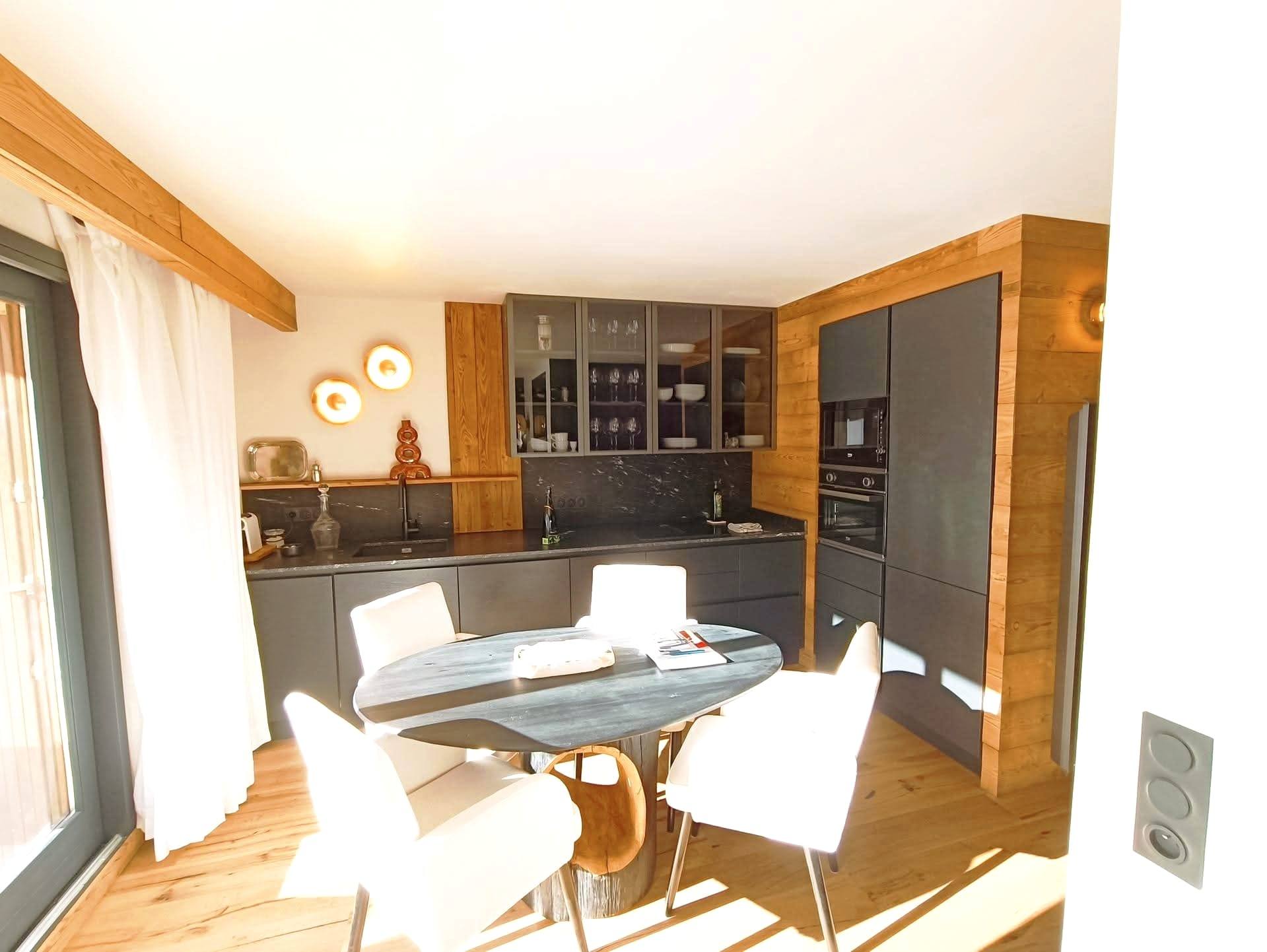 Cuisine rénovée avec façades anthracite, plan de travail clair et coin repas dans un appartement du Briançonnais