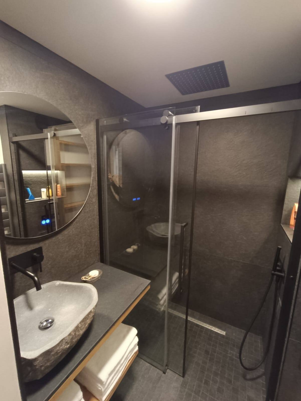 Salle de bain haut de gamme rénovée avec douche à l’italienne, carrelage ardoise, vasque en pierre et miroir rétroéclairé